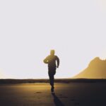 silhouette of unrecognizable man running on sand at sunset